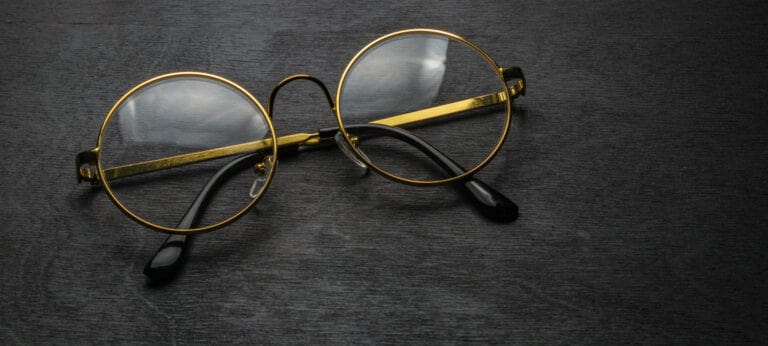 goldene Brille auf schwarzem Holz